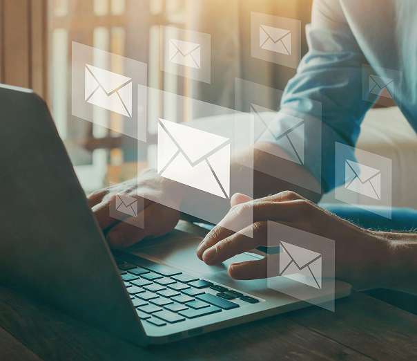 Mains tapant sur un ordinateur avec icônes d'e-mails, communication numérique